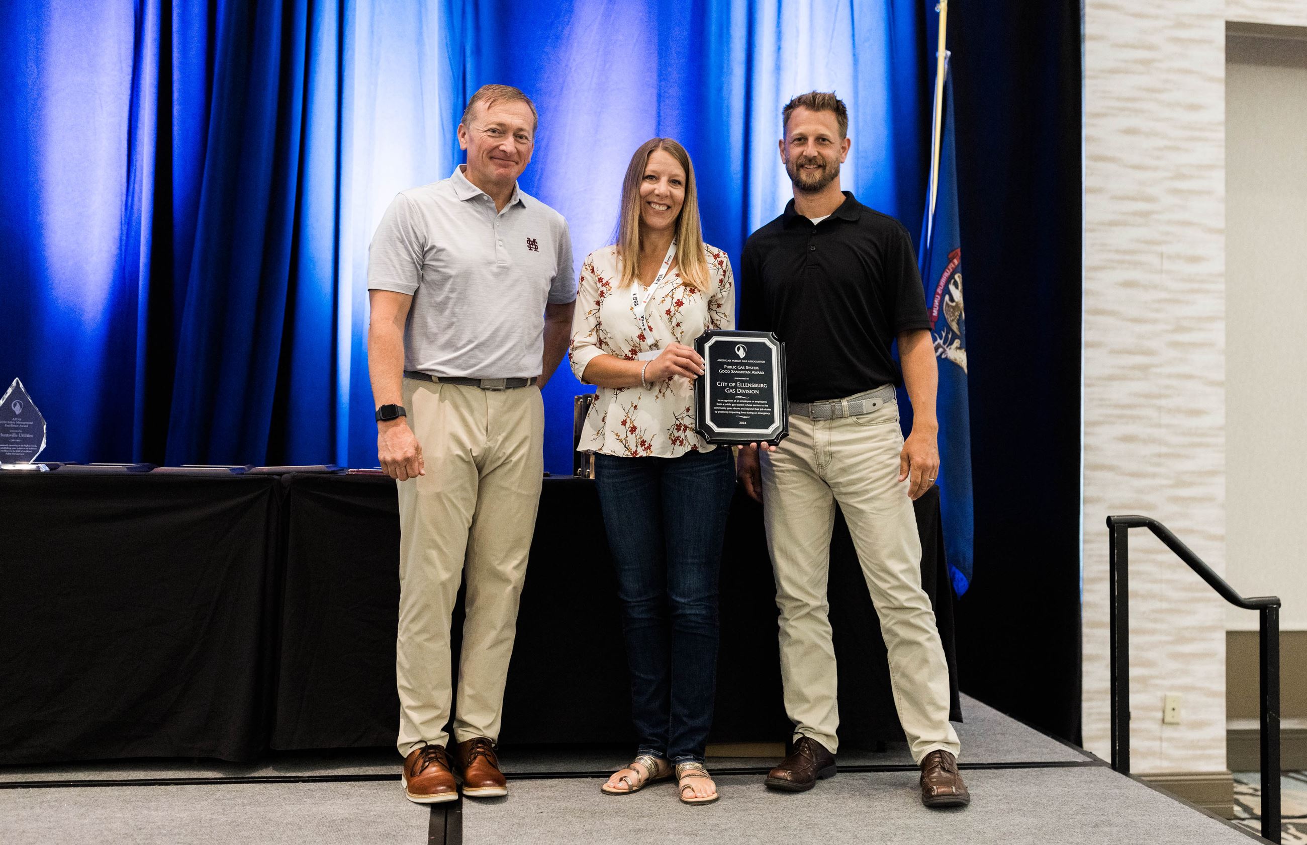 Three people pose with the APGA Award 